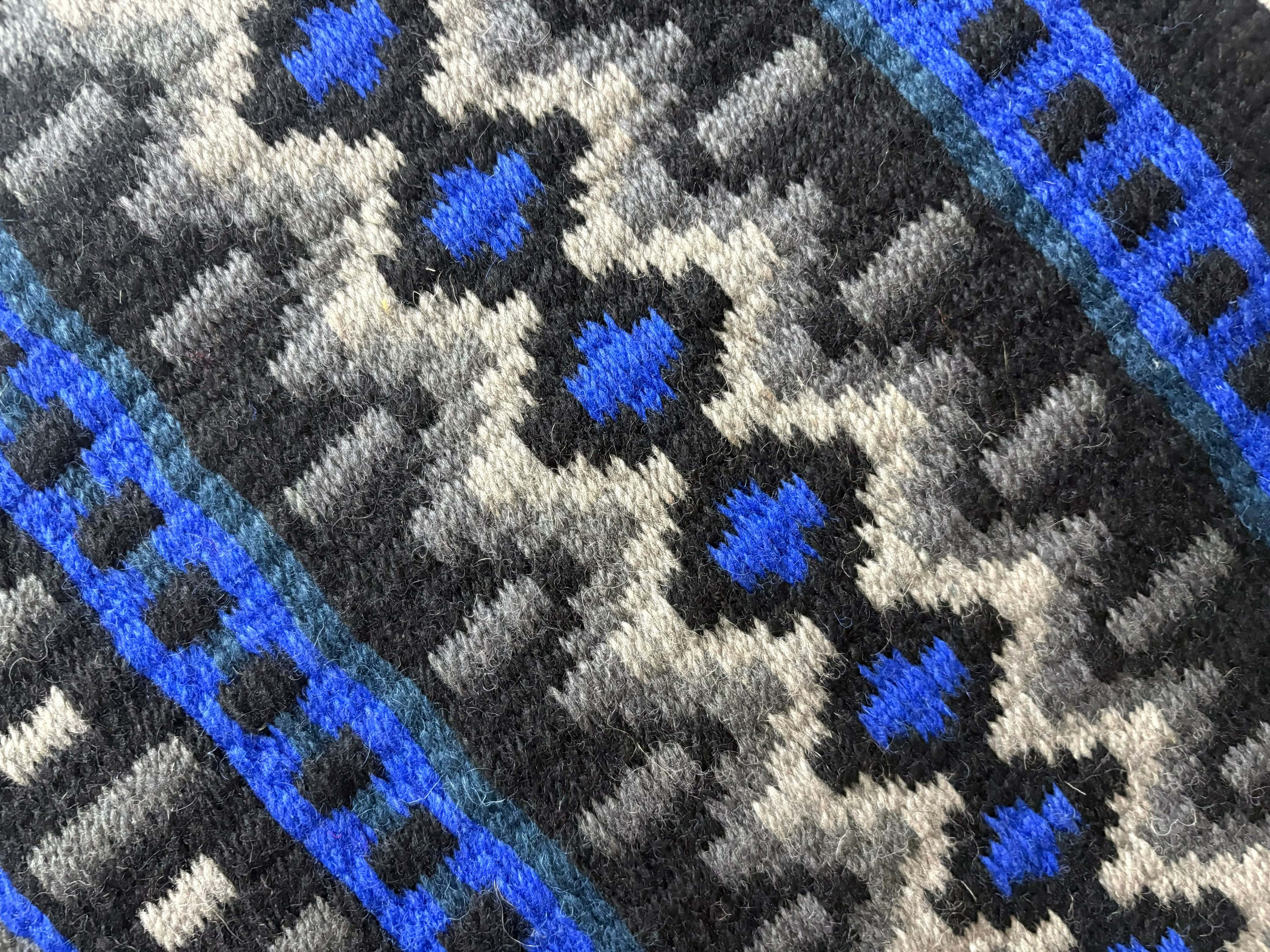 Extreme close-up detail of the tight handloom wool weave on a black, silver-grey, and royal blue geometric western show pad