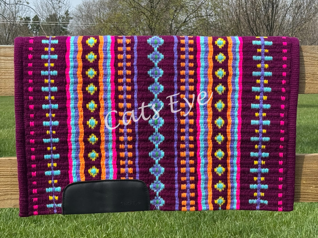 Hand-woven western show pad with a rich magenta plum-berry base featuring geometric patterns in bright orange, light turquoise blue, hot pink, purple, and yellow accents with black wear leathers.