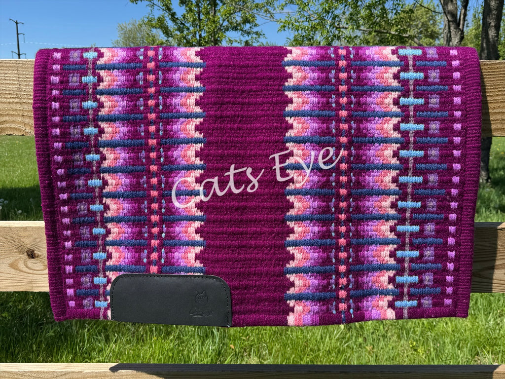 Hand-woven western show pad with a deep magenta berry base featuring geometric patterns in bright purple, soft pink, periwinkle, and light blue accents with black wear leathers. 