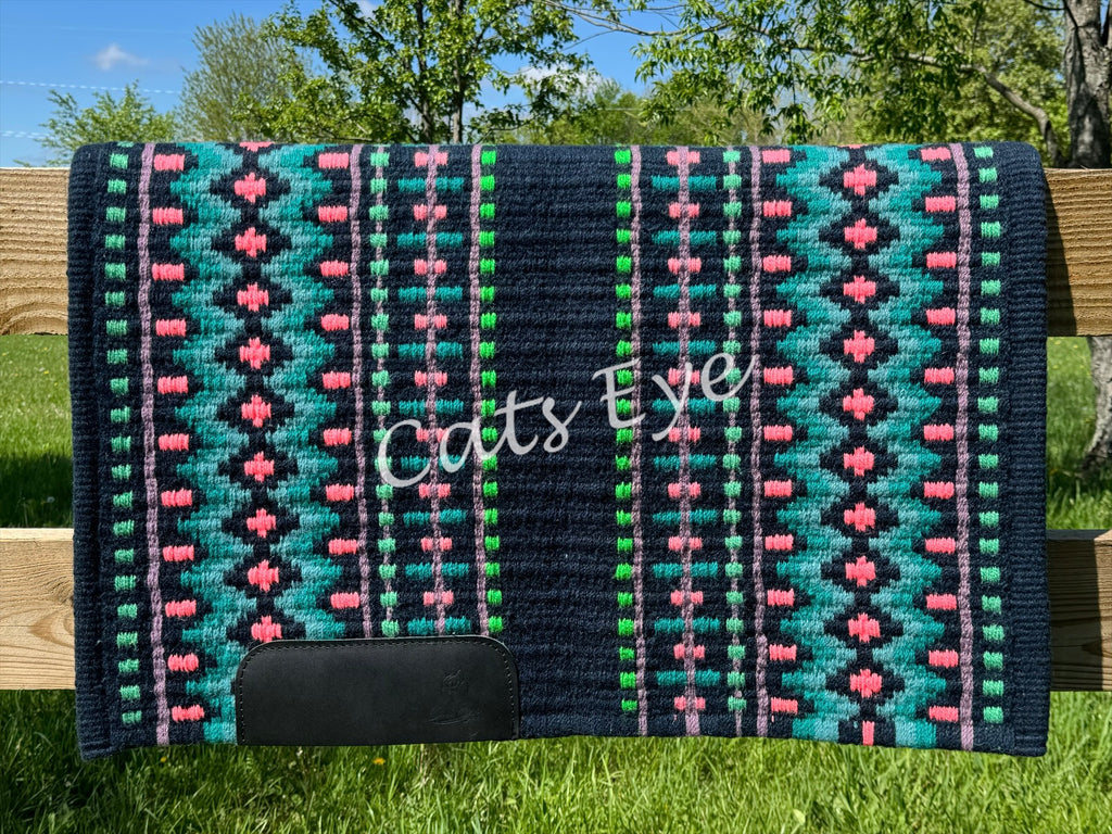 Hand-woven western show pad with a rich midnight navy blue base featuring geometric diamond patterns in bright turquoise, coral-pink, muted lavender purple, and vibrant lime green accents with black wear leathers.