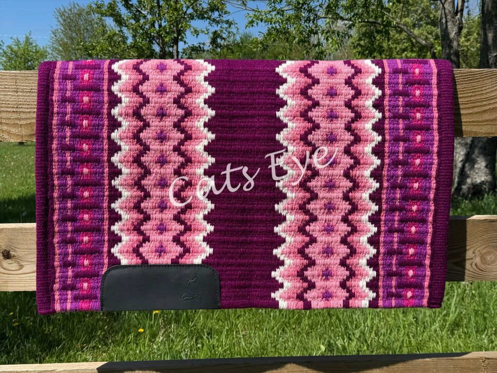 Hand-woven western show pad with a rich plum-berry base featuring geometric diamond patterns in light pink, white, dark magenta, and hot pink accents with black wear leathers. 