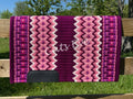 Hand-woven western show pad with a rich plum-berry base featuring geometric diamond patterns in light pink, white, dark magenta, and hot pink accents with black wear leathers. 