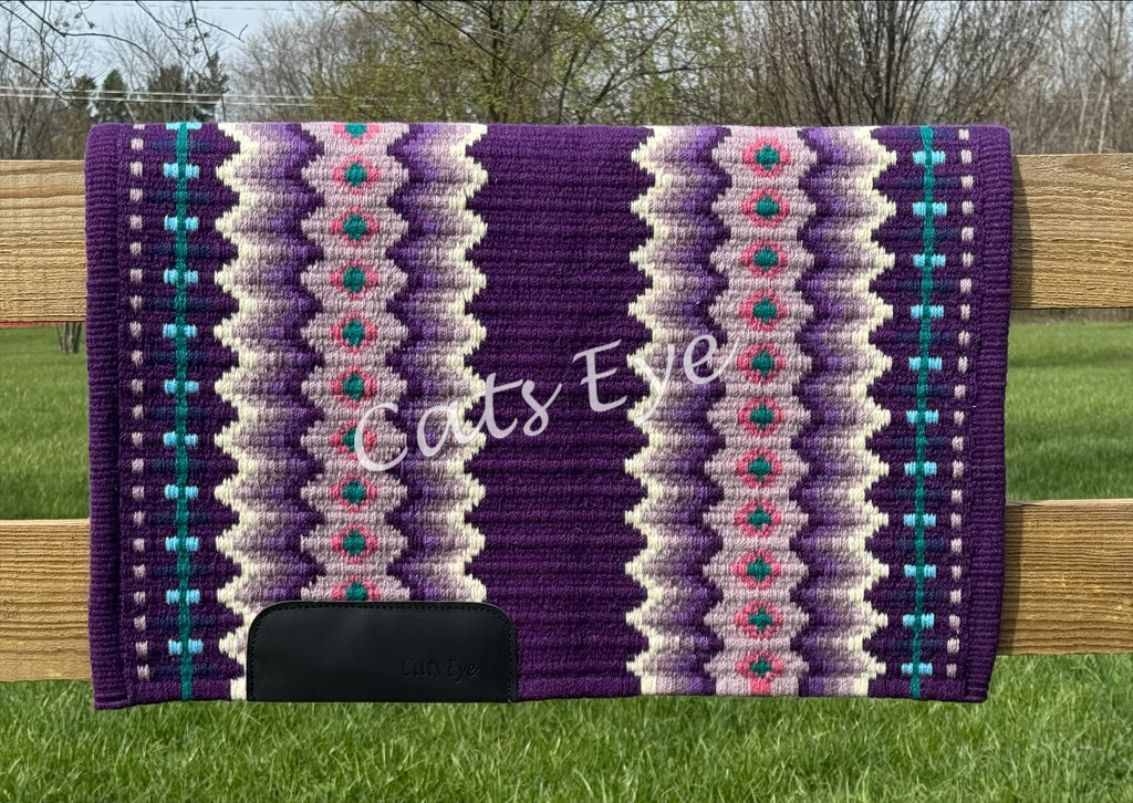 Hand-woven western show pad with a royal purple base featuring geometric diamond patterns in lilac, soft lavender, cream, bright pink, and teal accents with black wear leathers. 