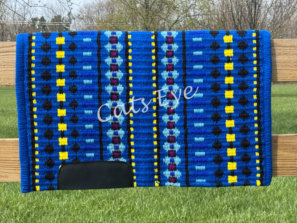 Hand-woven western show pad with a bright royal blue base featuring geometric diamond patterns in light turquoise blue, maroon, vibrant yellow, and black accents with black wear leathers.