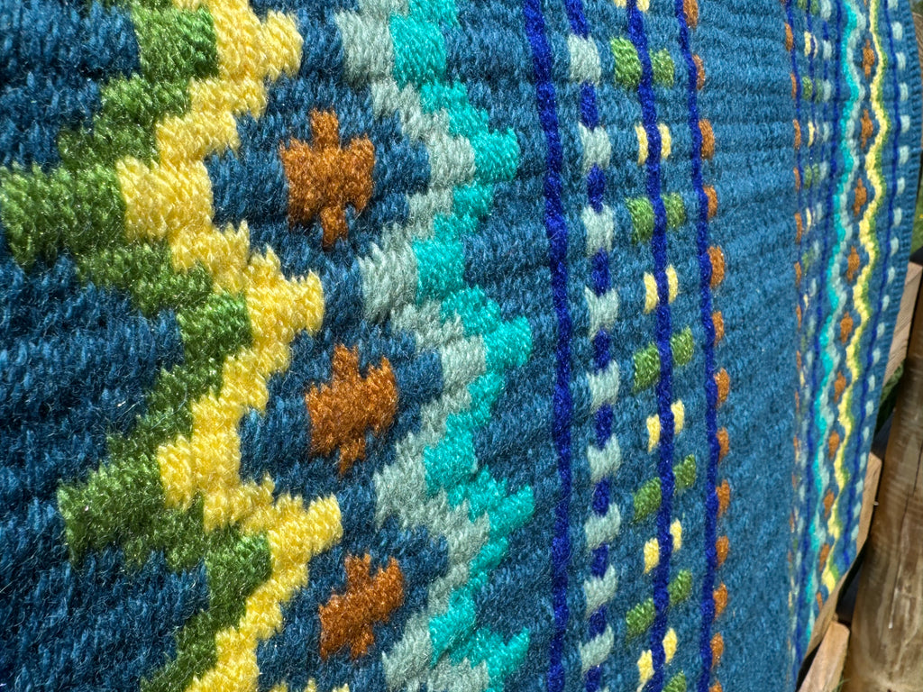Extreme close-up detail of the tight handloom wool weave on a rich teal blue geometric western show pad with lime green, bright yellow, royal blue, turquoise, and rust orange accents. 